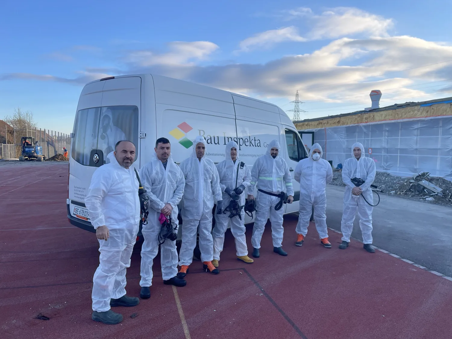Das Team der Bau Inspekta GmbH in Schutzausrüstung vor einem Firmenfahrzeug auf einer Sanierungsbaustelle